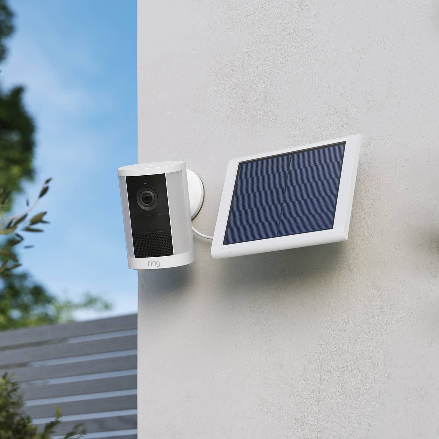 Spotlight Cam (Newest Model) - Solar:White Ring Spotlight Cam (2nd Gen) mounted to a wall with solar panel connected on a gray wall.