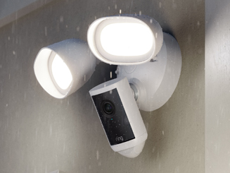 Rainy day with the white Floodlight Camera Pro (2nd Gen) mounted to wall outside and illuminated. 