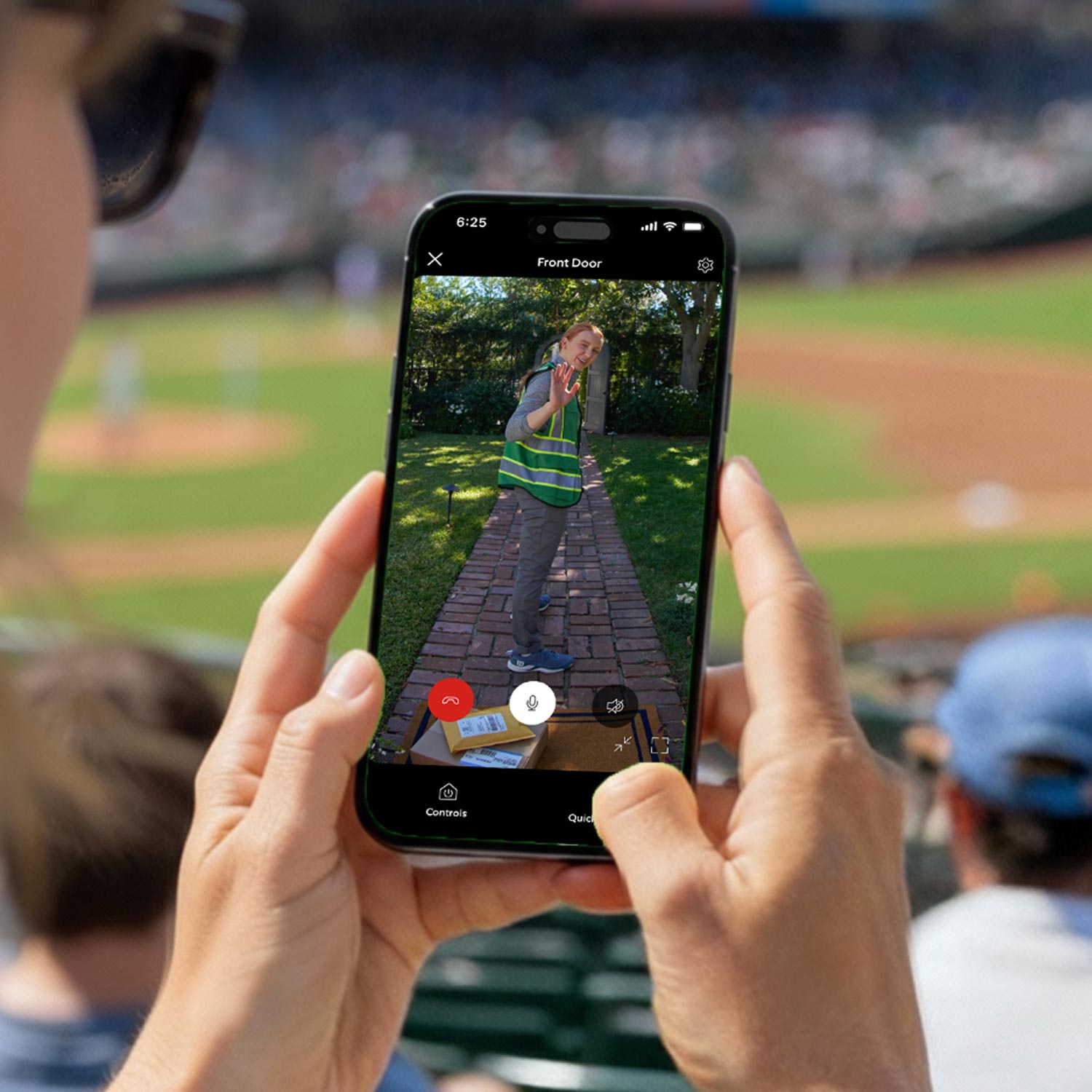 Phone screen shows a doorbell app with a delivery worker waving on a brick path and packages on the porch; user at a baseball game.