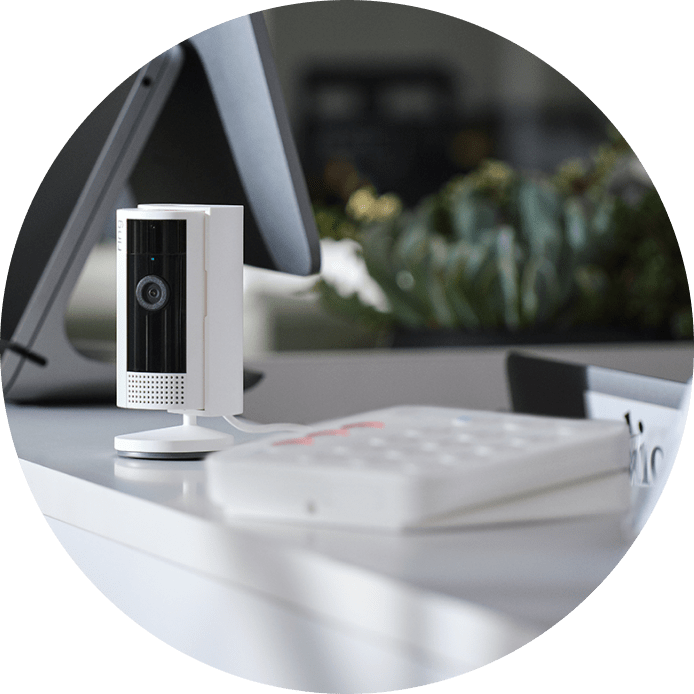 Ring camera next to a keypad on a white table. 