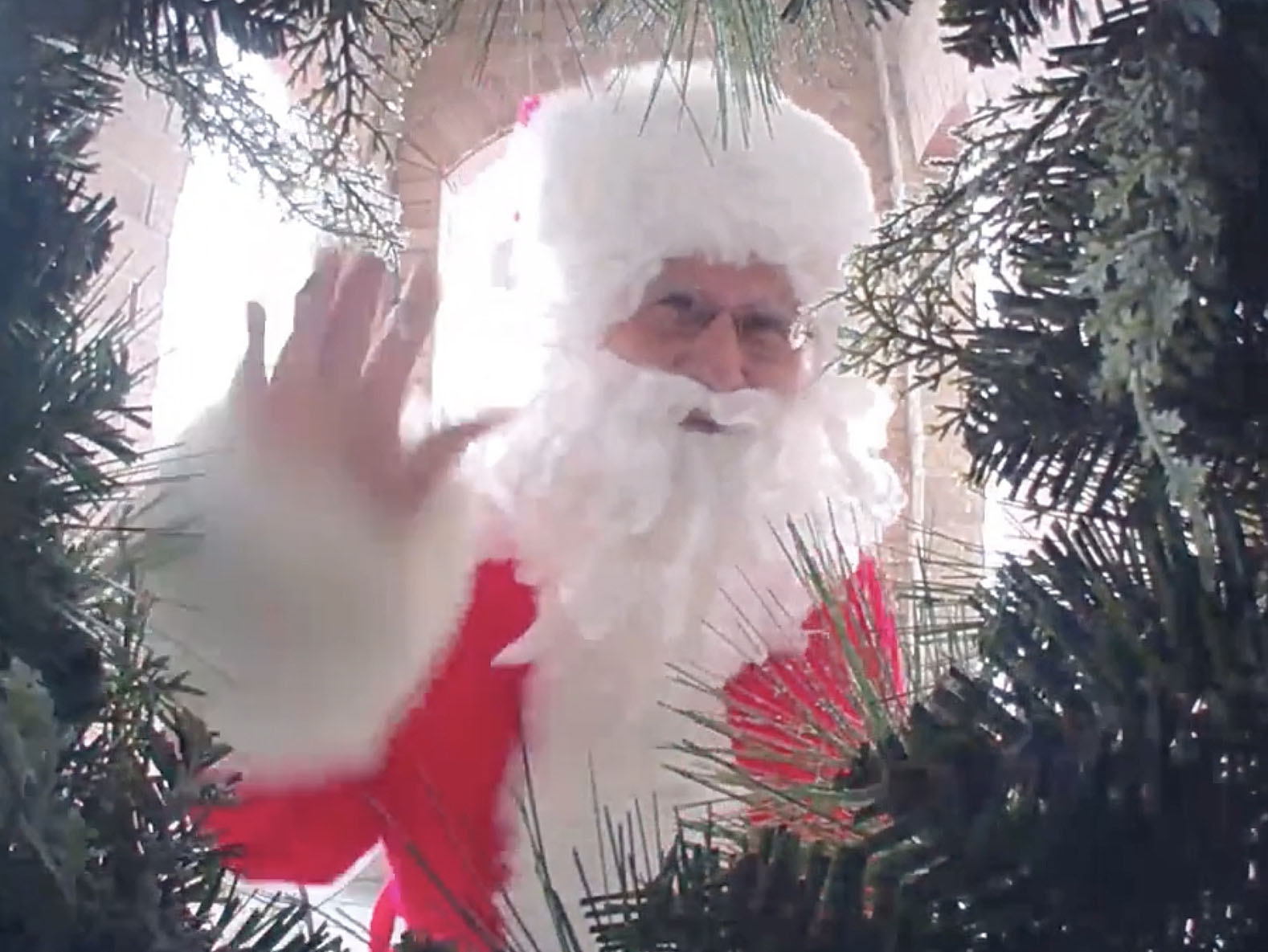 Person dressed as Santa Claus waving into the doorbell camera.