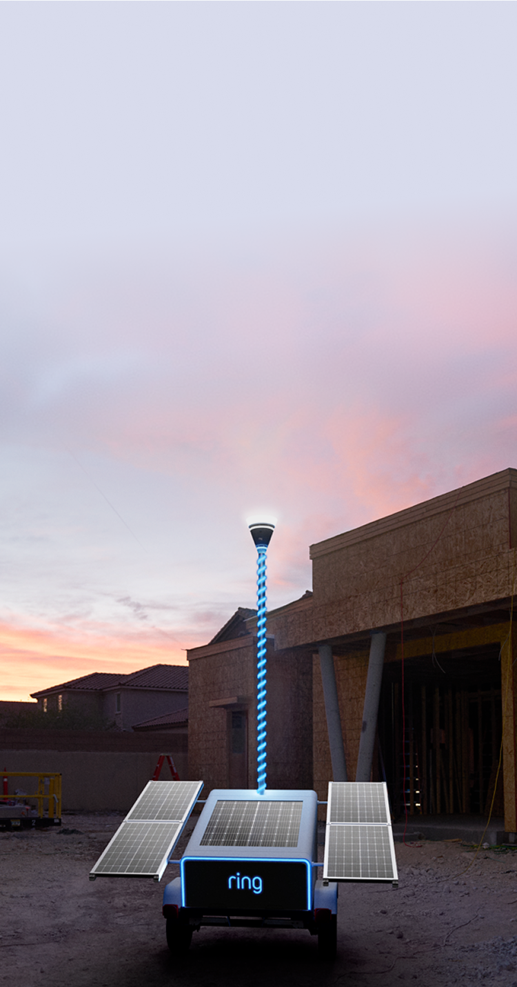 Solar-powered Ring mobile unit with a glowing blue mast at a construction site at dusk, flanked by extended solar panels and wood framing.