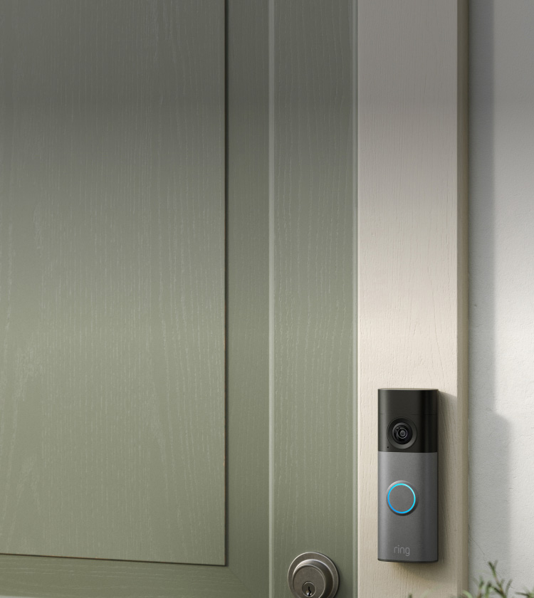 Smart video doorbell with glowing blue ring mounted beside a green front door and silver deadbolt, on a white exterior wall.