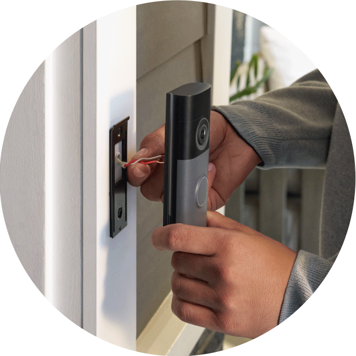 Close-up of hands installing a Wired Doorbell Pro (2nd Gen), showing the placement of the device against a dark doorframe surface for mounting.