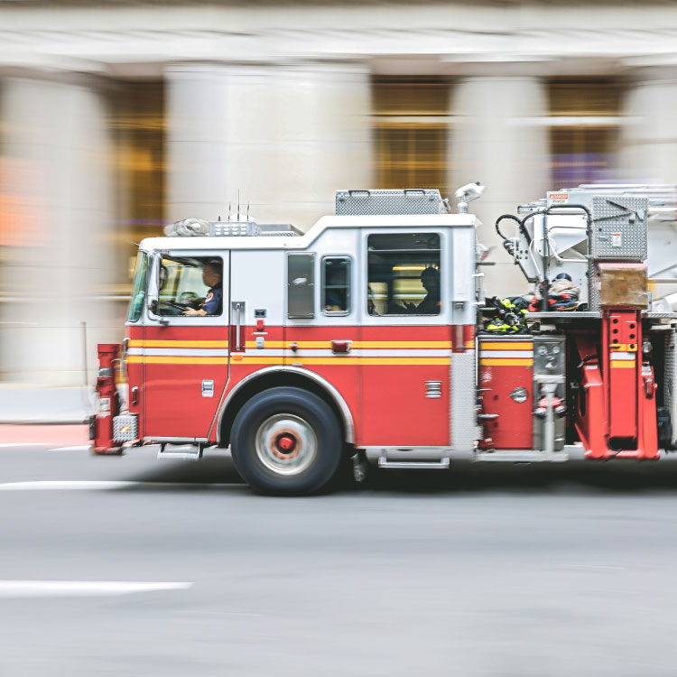 A fire truck is driving quickly through a city in response to an emergency. 
