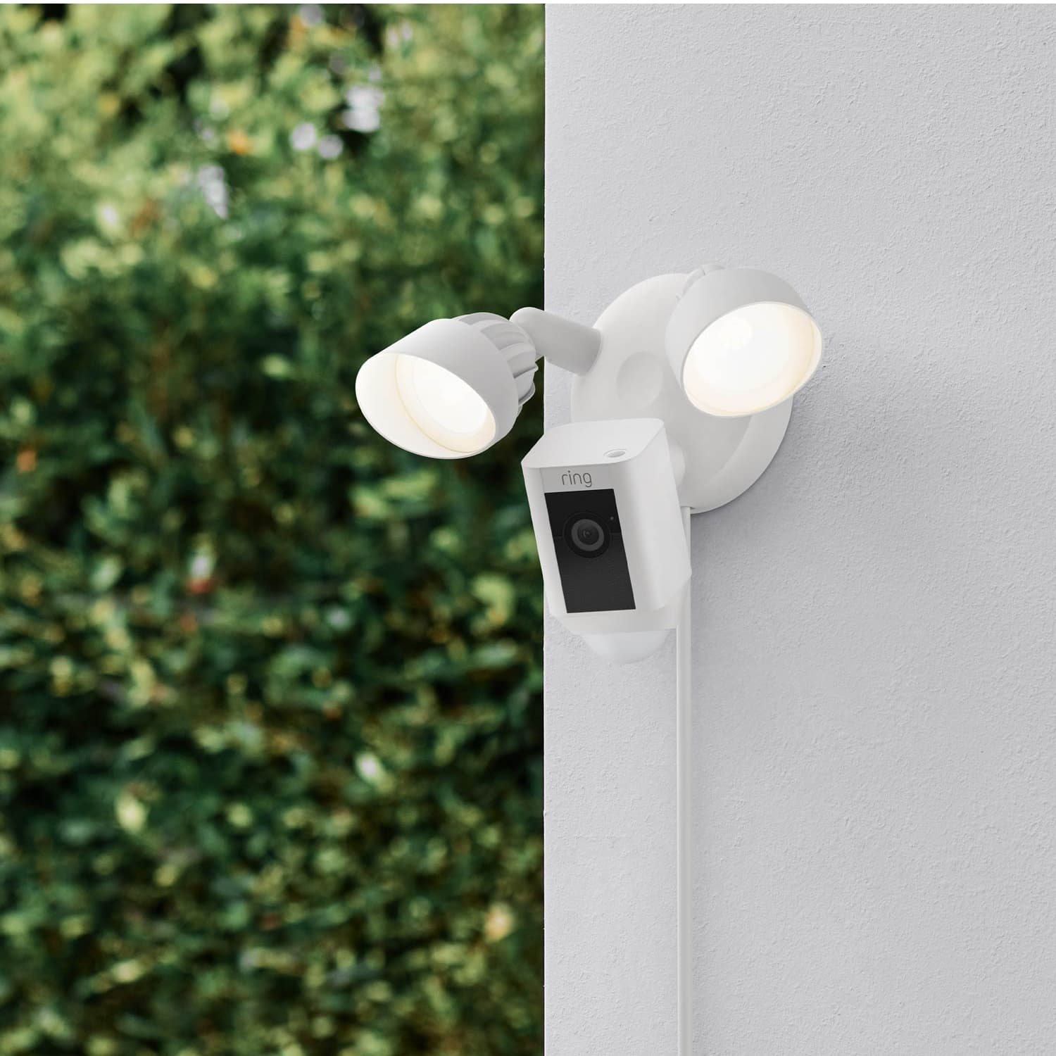 Floodlight Cam Plus (Plug-In) - Floodlight Cam Plus, Plug-In model in white mounted to exterior corner of home with both lights on.