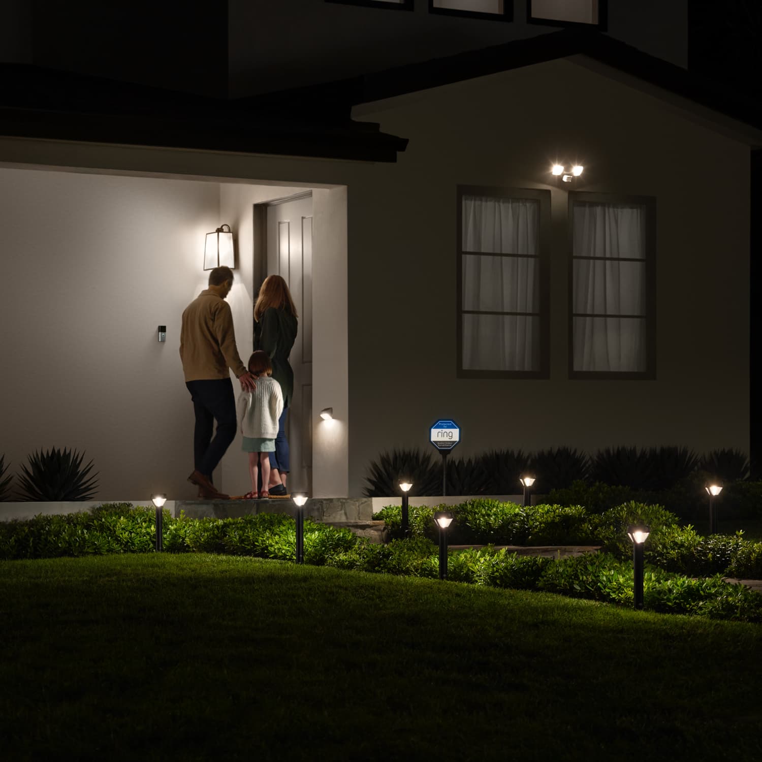 Smart Lighting Solar Pathlight - Outdoors at night, a family approaches the front door of a home. The pathway is illuminated by Solar Pathlights.