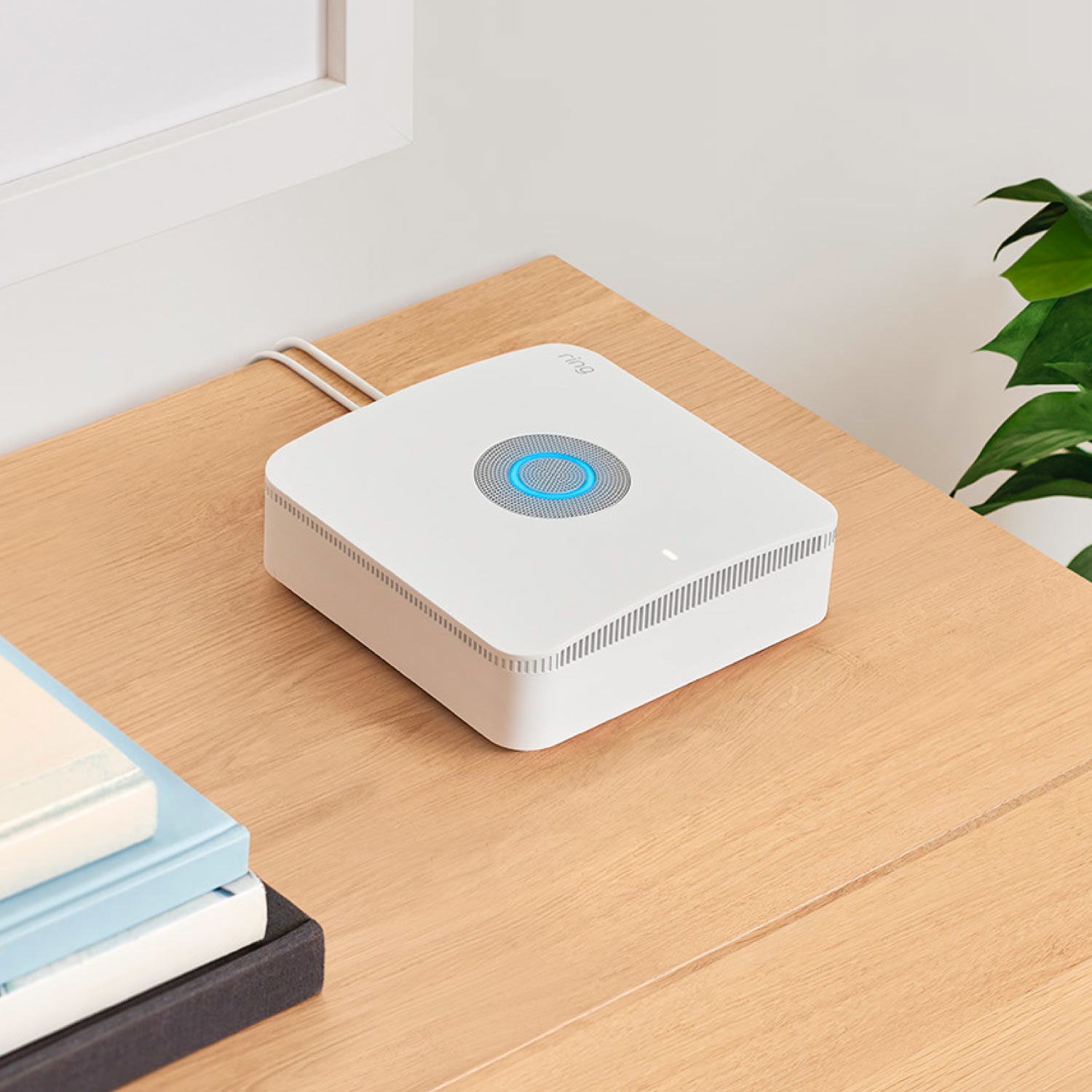 Alarm Pro Security Kit, 8-Piece (with built-in eero Wi-Fi 6 router) - Alarm Pro Base Station situated on wooden desktop next to some books.