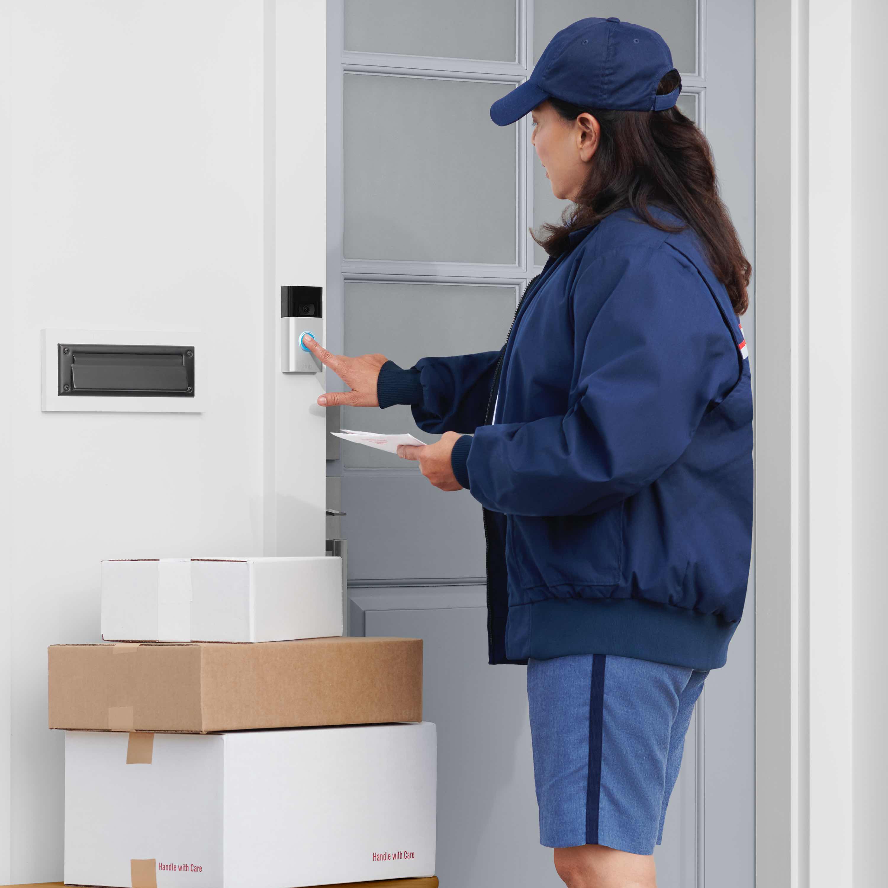 Video Doorbell (2nd Generation) (for Certified Refurbished) - Postal worker with packages pressing button on Video Doorbell 2nd Generation mounted next to front door of home.