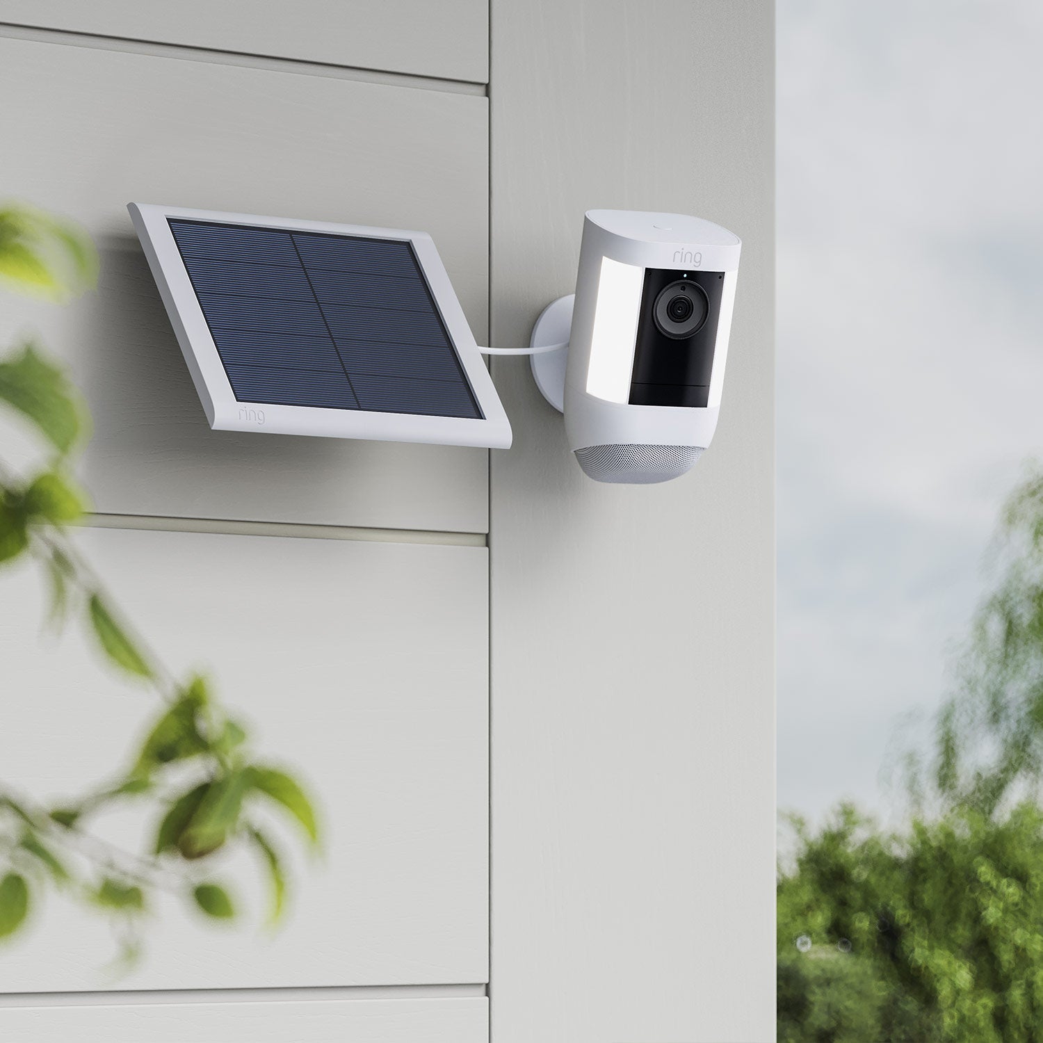 Spotlight Cam Pro (Solar) - Spotlight Cam Pro and solar panel, both in white, mounted on exterior wall of home.