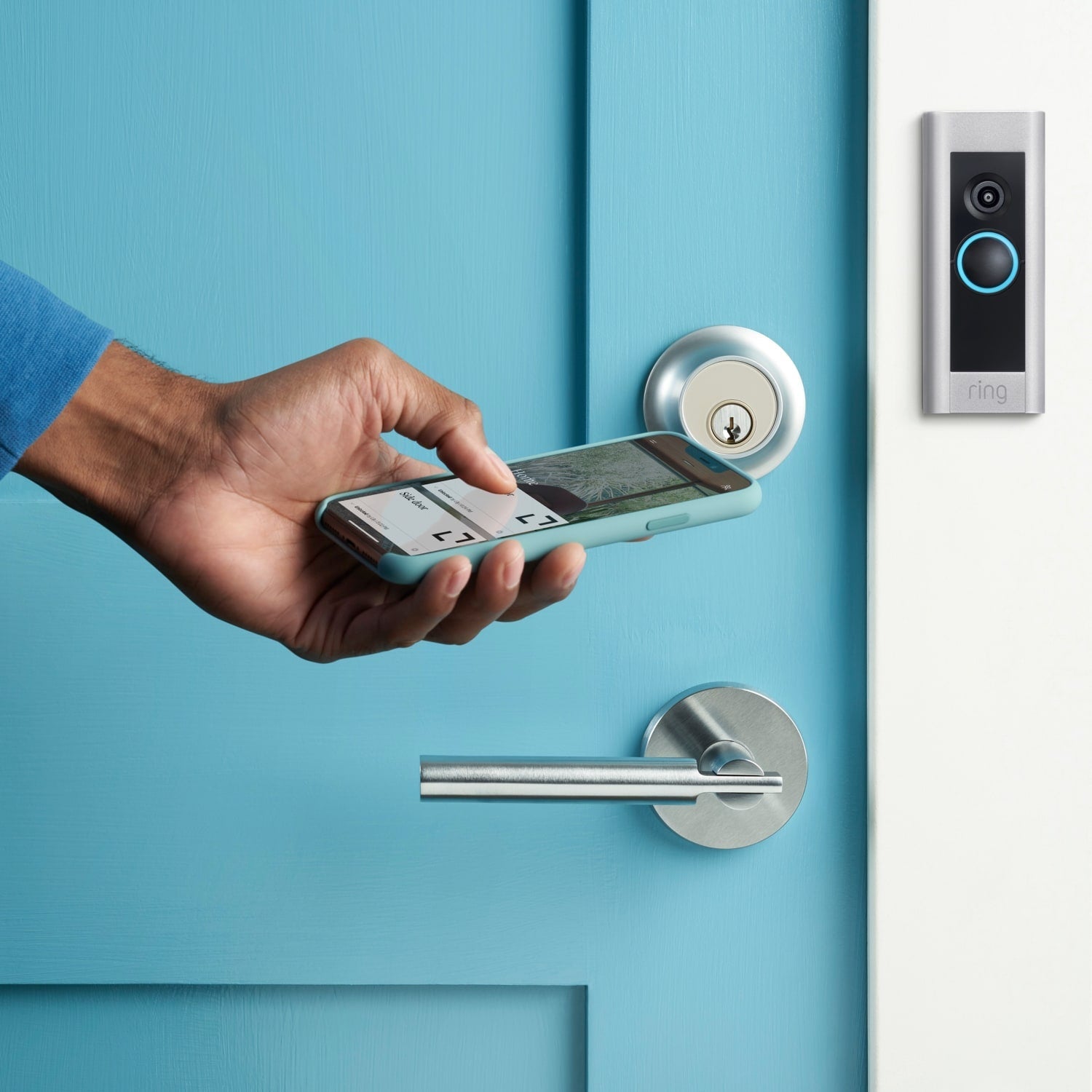 Wired Doorbell Plus (Video Doorbell Pro) (for Certified Refurbished) - Close-up of hand holding smartphone in front of a door with a Video Doorbell Pro mounted next to it.
