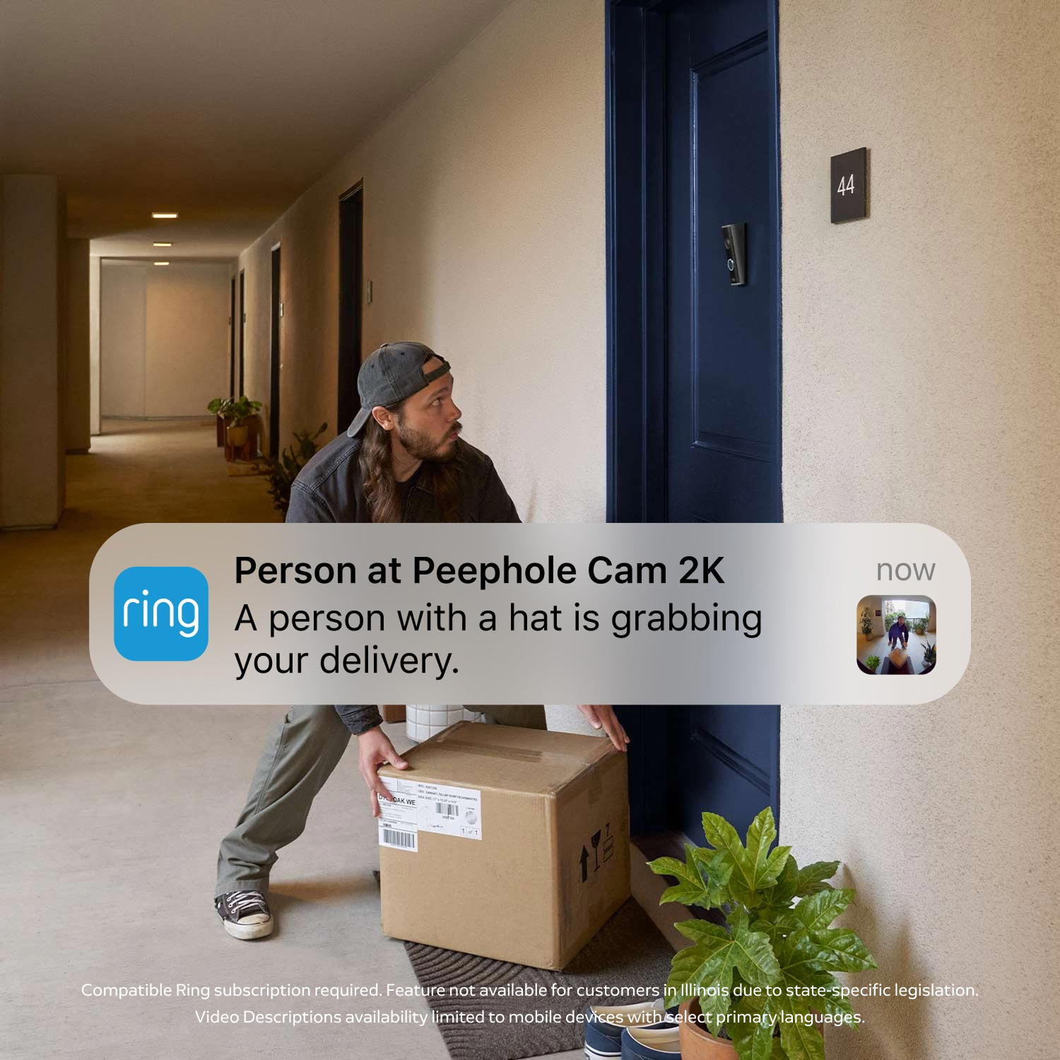 Apartment hallway with a blue door scene with a person in a cap bends to lift a large cardboard package by the doorstep.