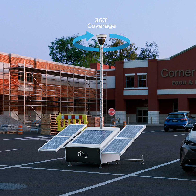 Solar-powered Ring unit with raised 360° camera in a parking lot near a brick building and scaffolding, cars parked nearby.