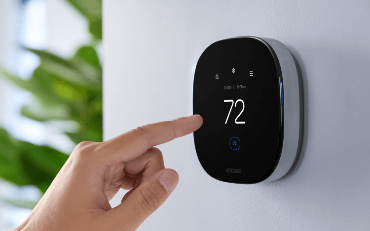 Hand adjusting Smart Thermostat Premium against white wall.