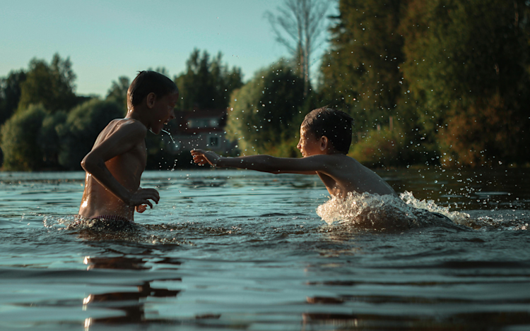 Two kids having fun playing in a lake, splashing water.