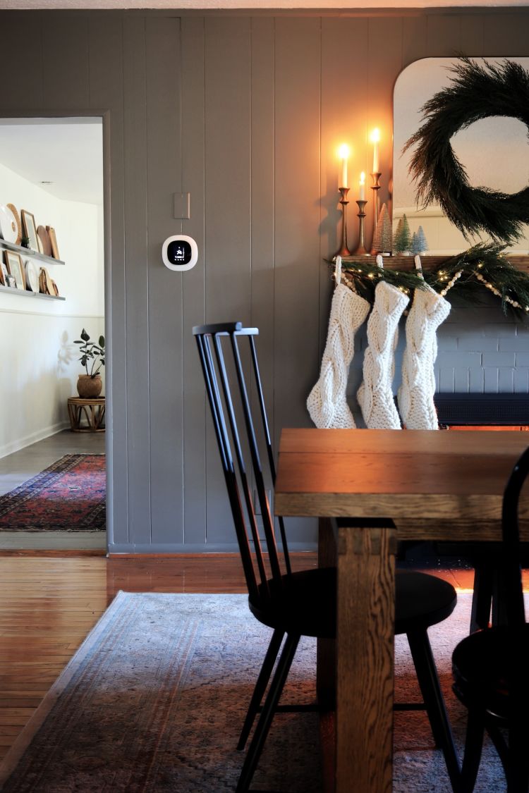 ecobee SmartThermostat with voice control on wall with wreath, stockings, and a fireplace beside it. 