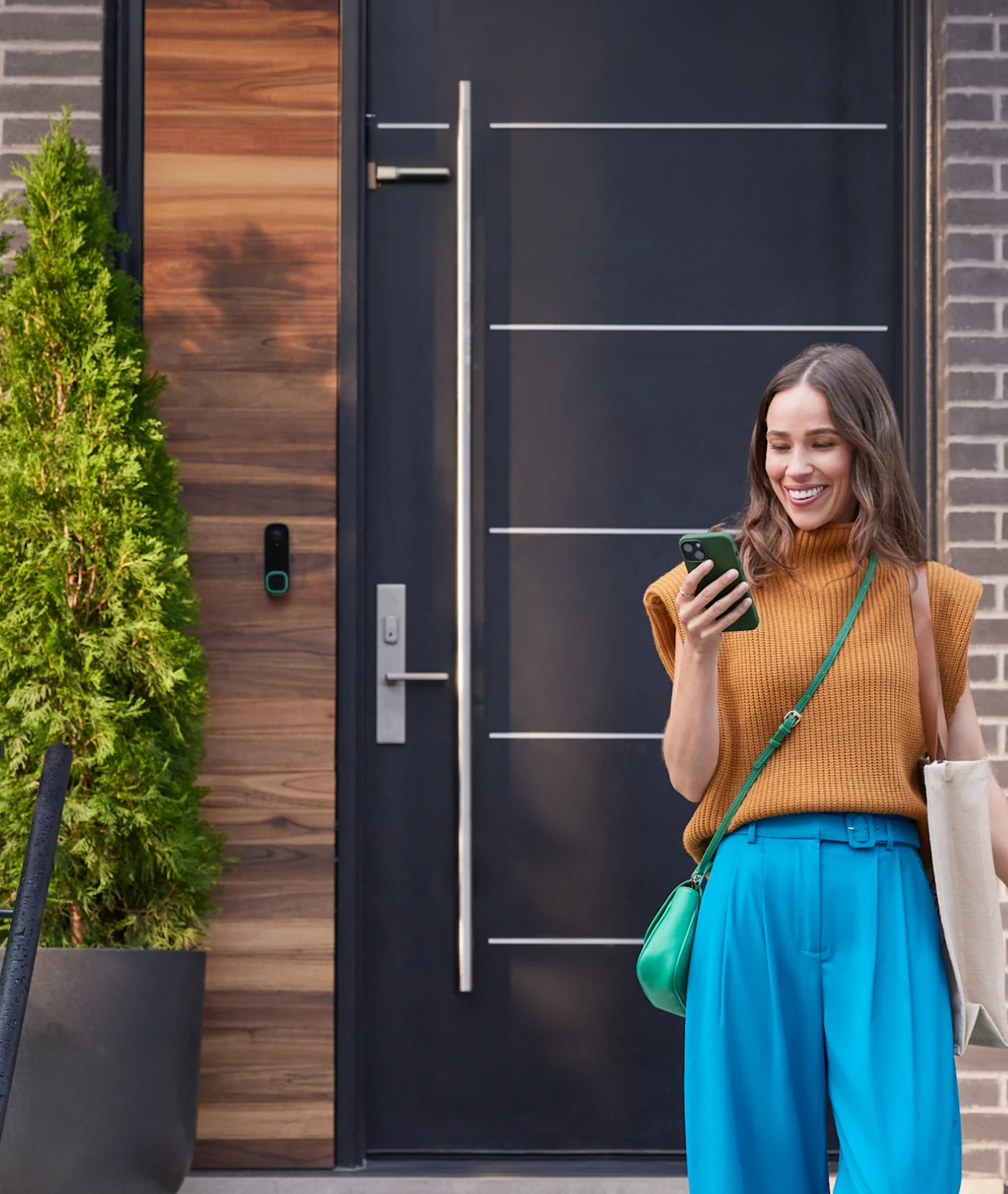 caméra de sonnette intelligente ecobee sur une maison, une femme regarde son téléphone et voit une notification de l’application ecobee