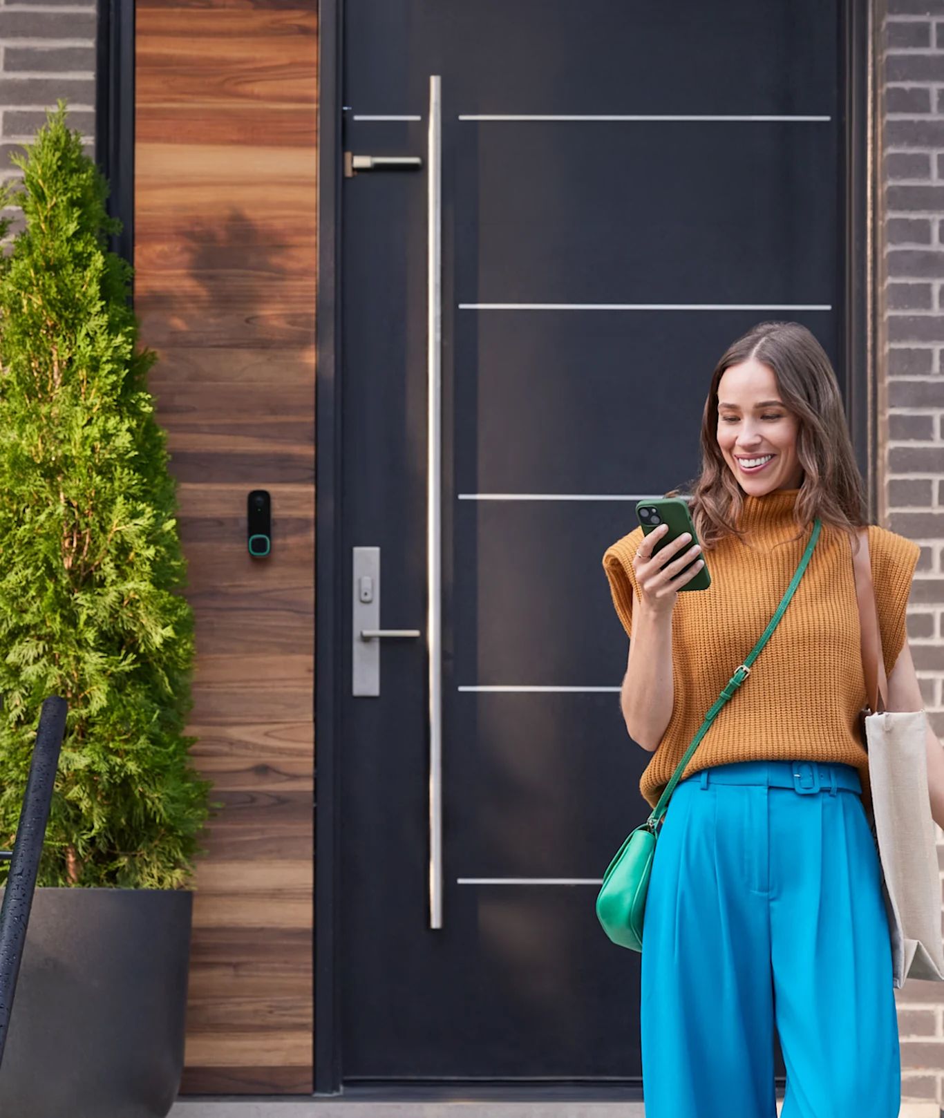 caméra de sonnette intelligente ecobee sur une maison, une femme regarde son téléphone et voit une notification de l’application ecobee