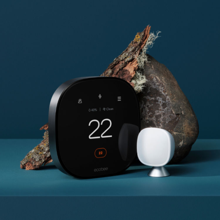 Smart Thermostat Premium shown at a three quarters angle view with a SmartSensor placed to the right of it. A rock and piece of bark are artfully placed behind the two products. The background is a rich blue colour. 