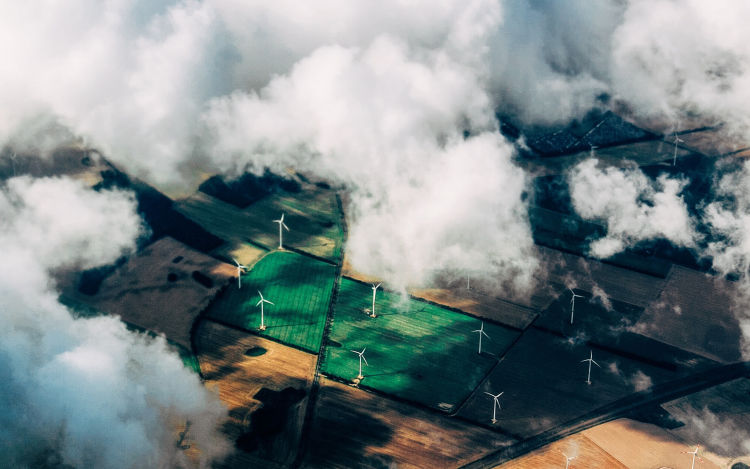 View of wind farm from above the clouds. eco+ is helping to decarbonize the world by making homes more energy-efficient. 