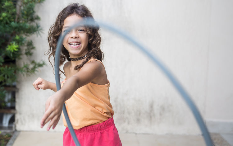 Child smiling while playing with hula hoop. 