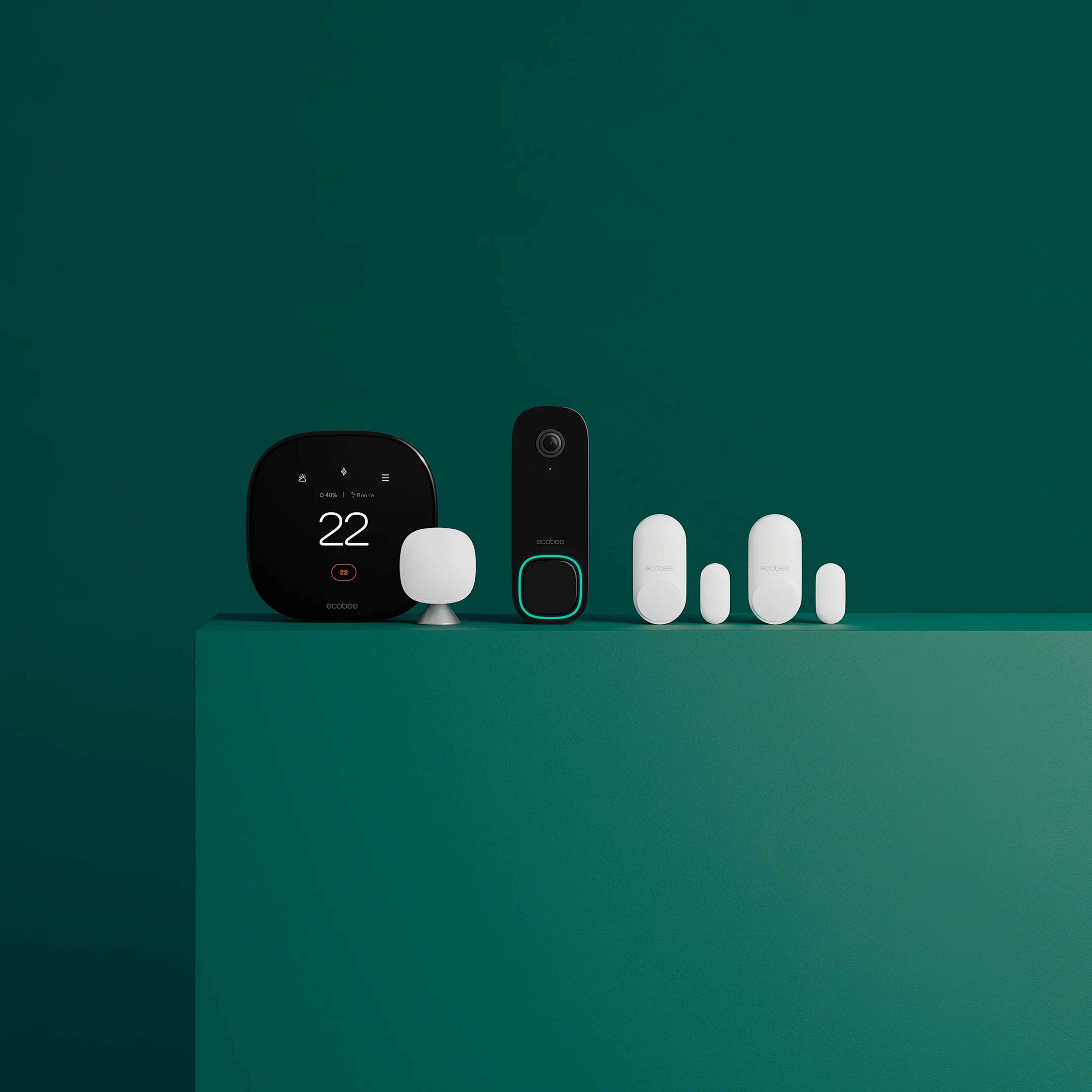 thermostat ecobee, caméra de sonnette intelligente et capteurs posés sur un rebord vert devant un fond vert.
