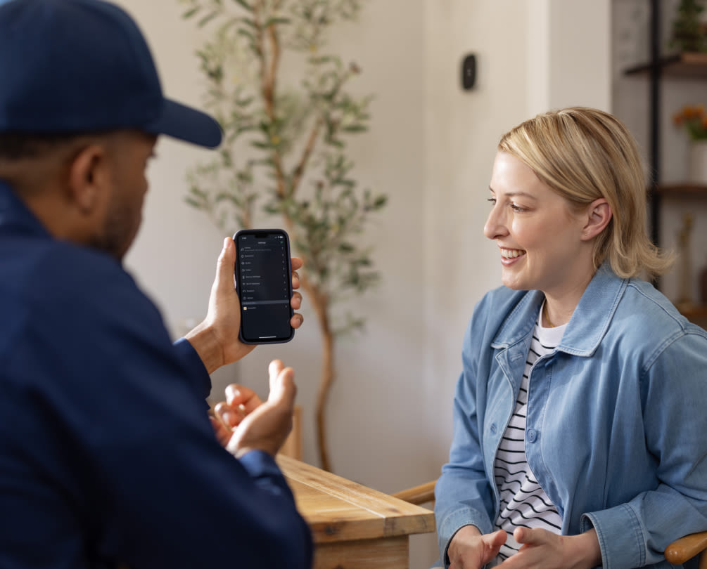 a pro installer shows a woman the ecobee app on a phone