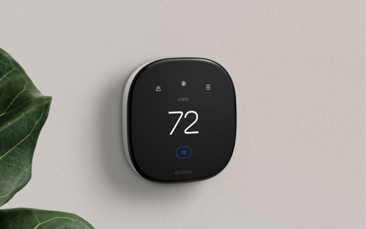 An ecobee smart thermostat hanging on the wall with the screen displaying the home temperature