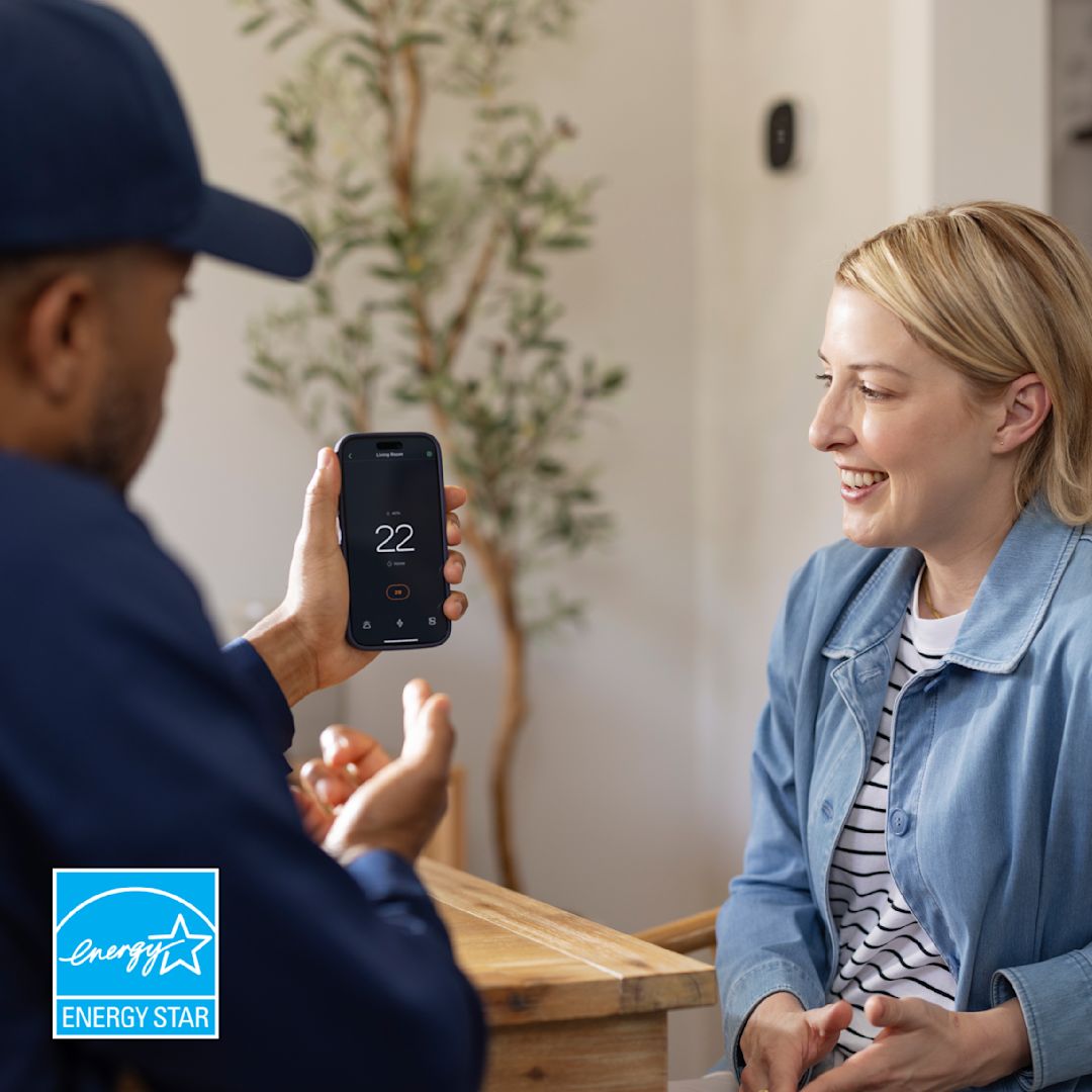 technician shows a person how to control their thermostat from their phone