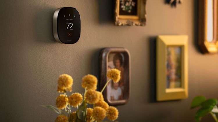 ecobee Smart Thermostat Premium displaying 72°F on a wall surrounded by framed photos and artwork.