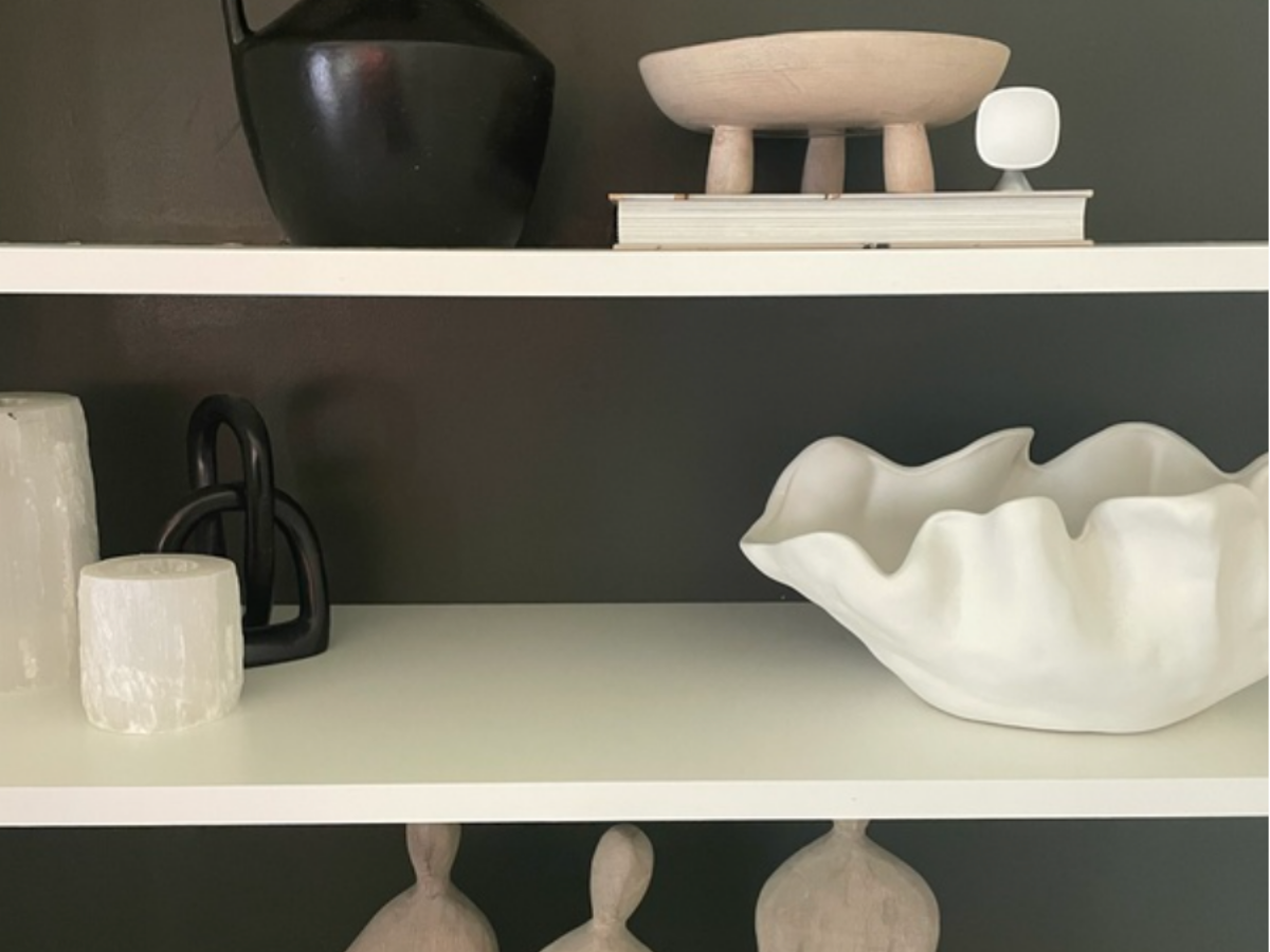 A Smart Sensor sits on a white book shelf blending in seamlessly surrounded by modern decor items.  