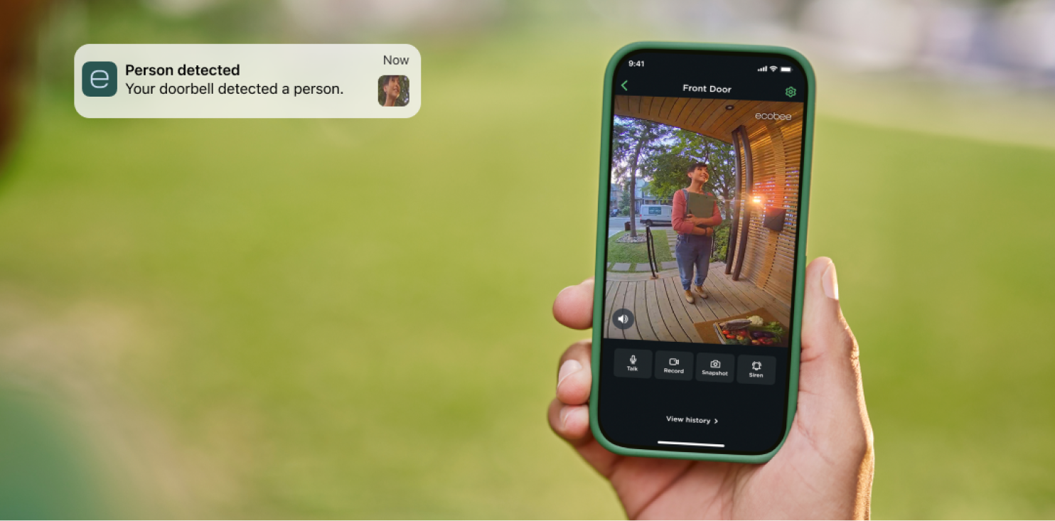 A hand holding a phone with the ecobee app open. The app screen is showing the front door view, with a woman standing at the front door.