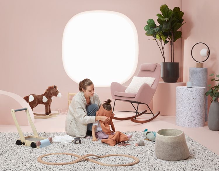 Child and caregiver being looked after in nursery with toys.