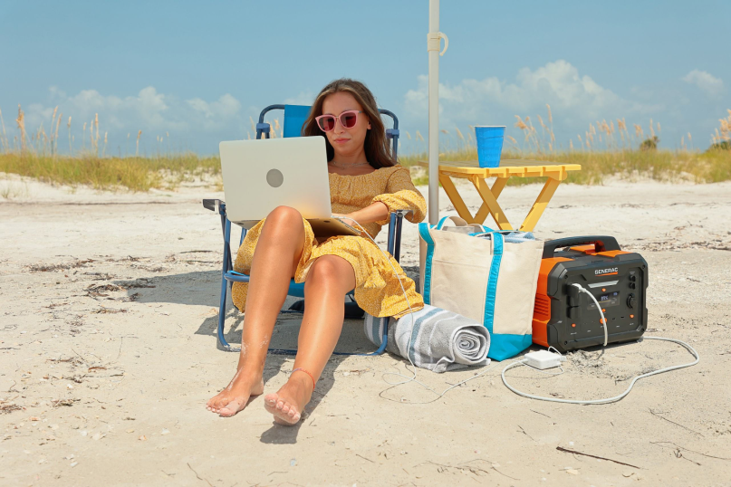 Woman sitting on beach chair working on laptop with GB1000 powering it.