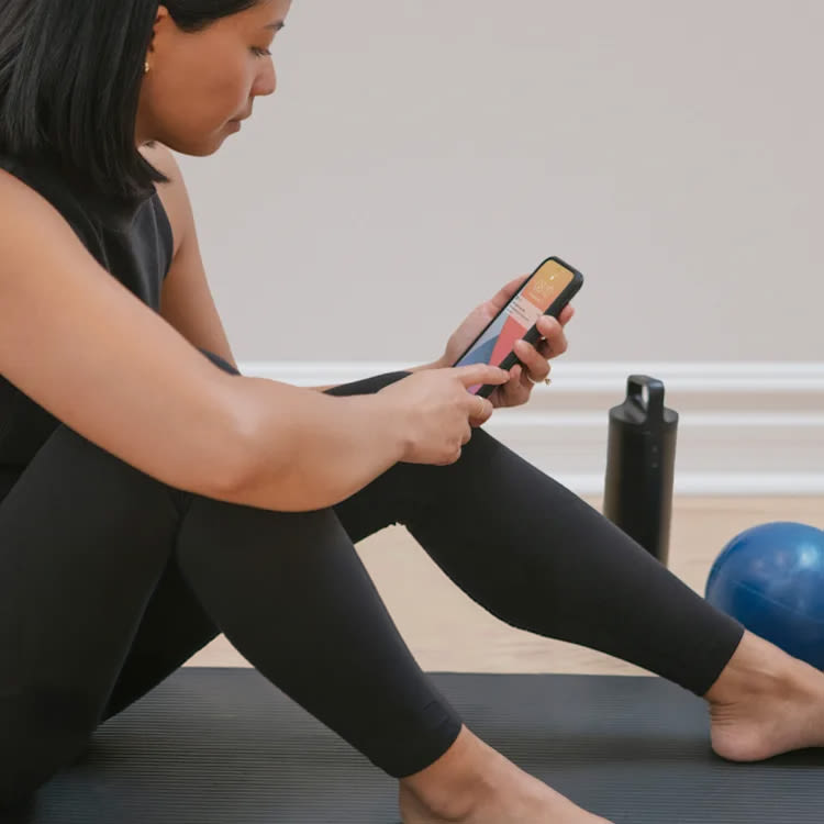 Une femme consulte son téléphone pendant son entraînement; une notification de l'application ecobee indique « Alerte d'activité - Mon domicile »