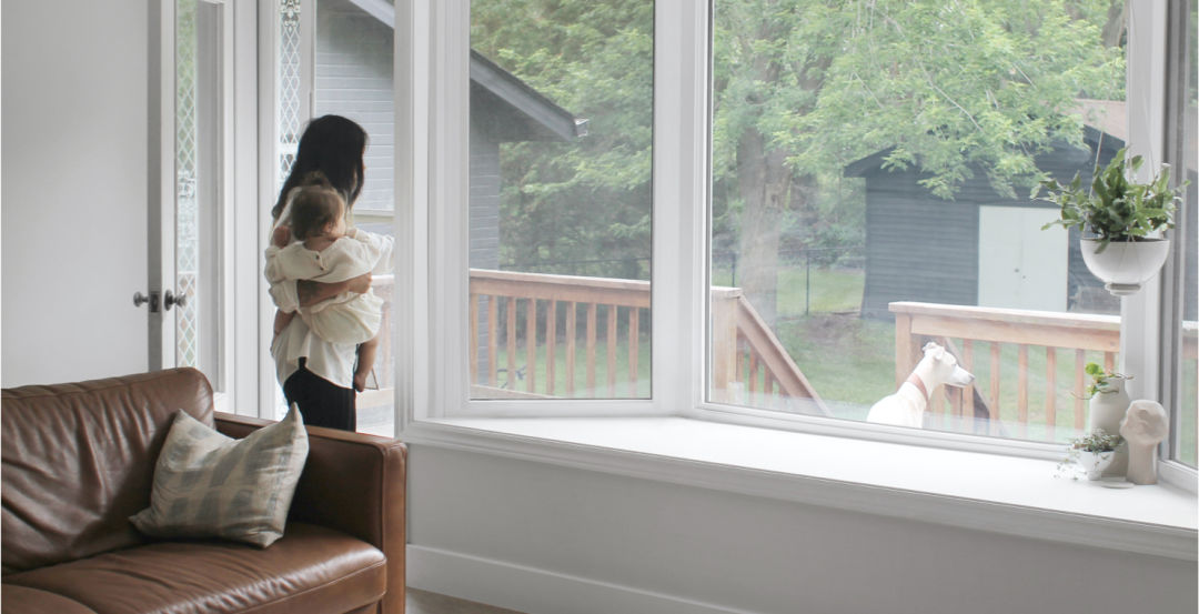 A woman holding a baby looks out a window.