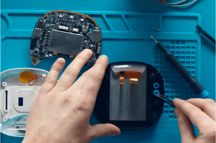 A pair of hands works on the internal hardward of an ecobee thermostat.