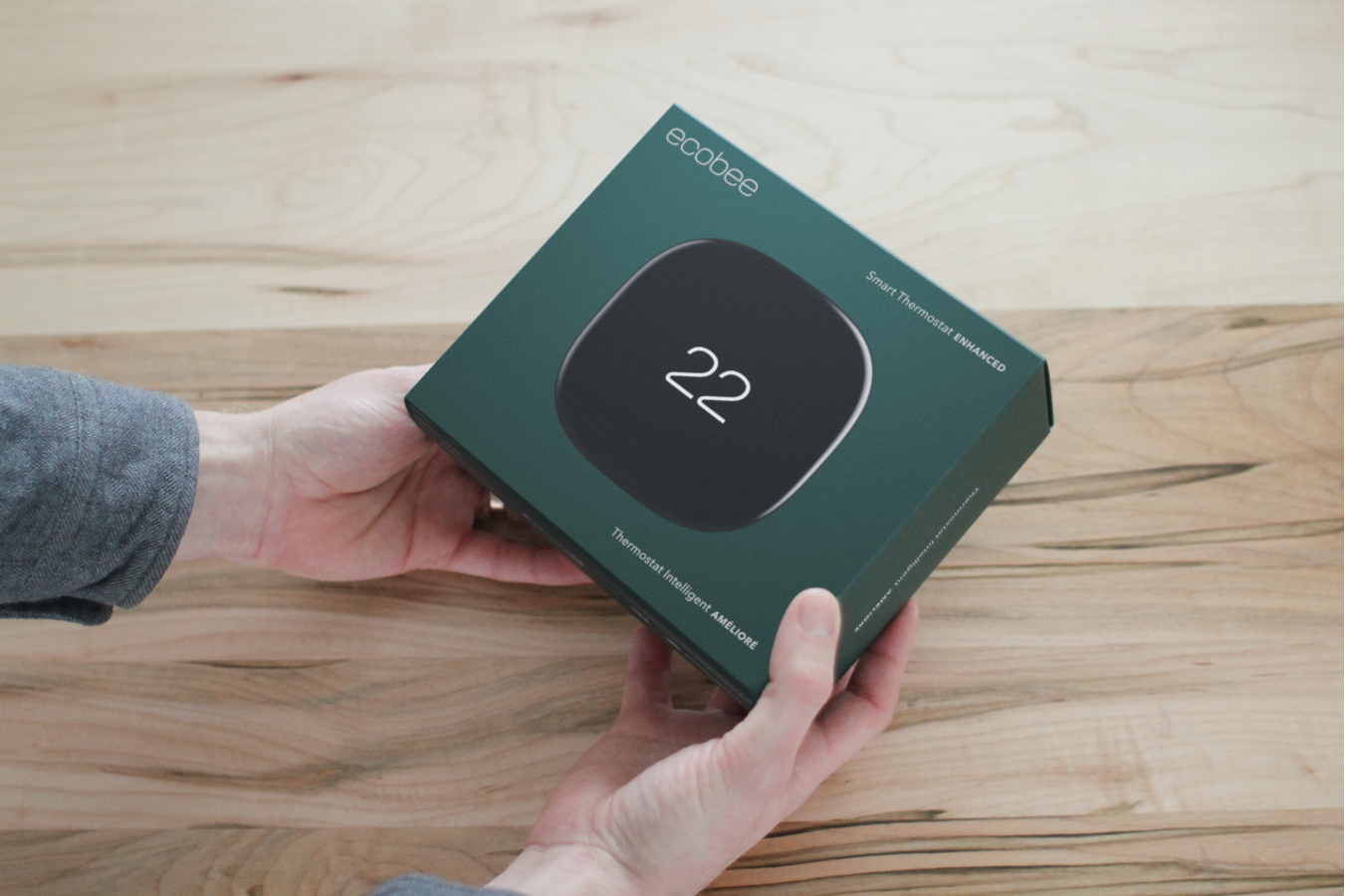 a pair of hands holds the box for ecobee smart thermostat enhanced