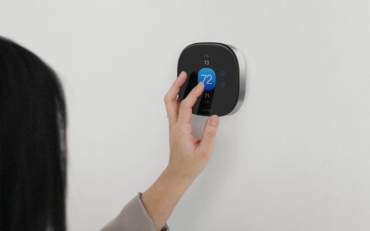 A woman adjusting the temperature settings on her ecobee Smart Thermostat Premium installed on a wall