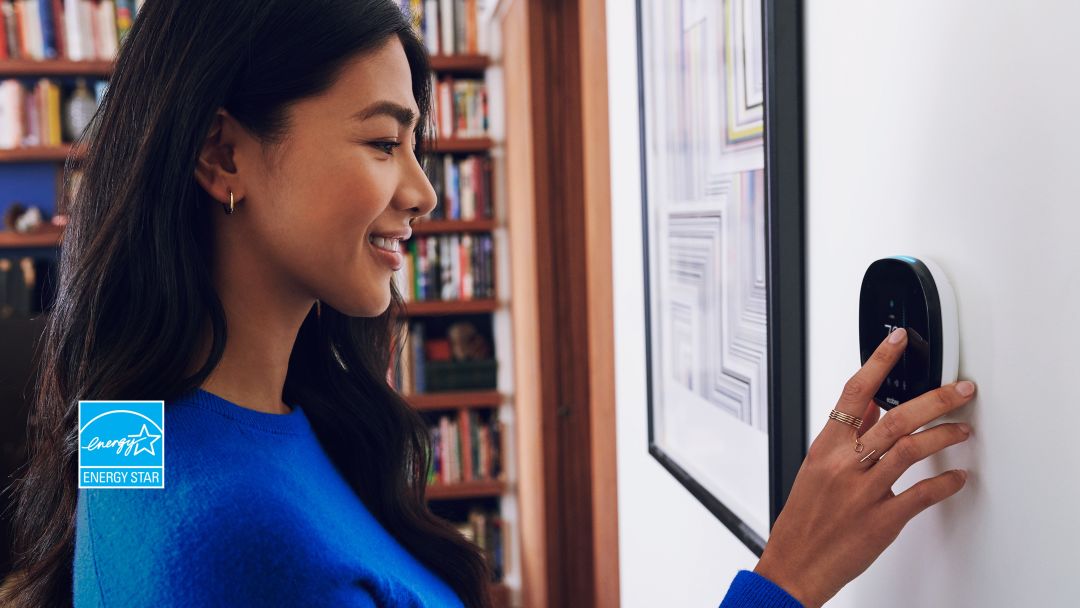 Lady in blue shirt using her ecobee thermostat's touchscreen