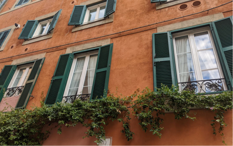 Image of a European building from the outside, with shutters over the windows and no air conditioning 