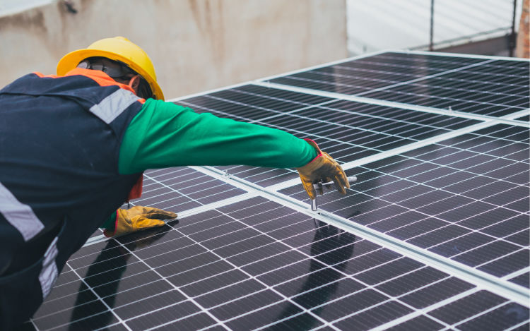 A contractor installing solar panels on the roof of a house