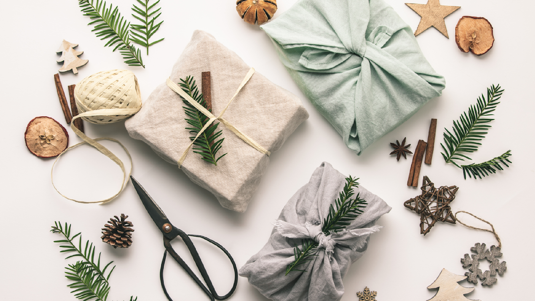 Gifts sitting on a table wrapped in sustainable materials, including cloth, rope and pine cones.