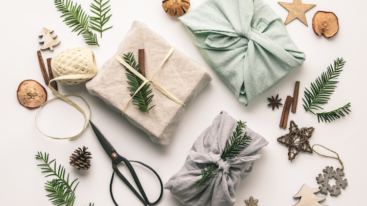 Gifts sitting on a table wrapped in sustainable materials, including cloth, rope and pine cones.