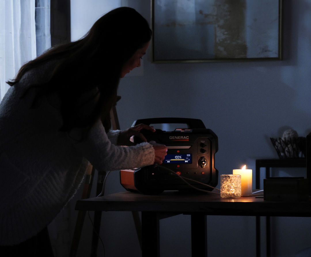 A person turns on the GB1000 Portable Power Station in a dark room with candles