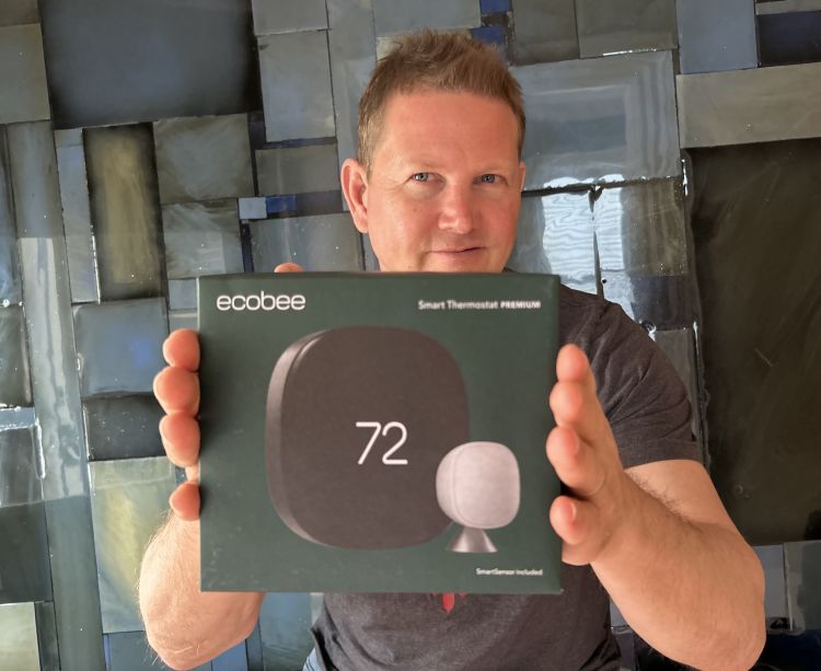 Vice President of Creative and Design Jonathan Hayes holding green packaging of ecobee's Smart Thermostat Premium.
