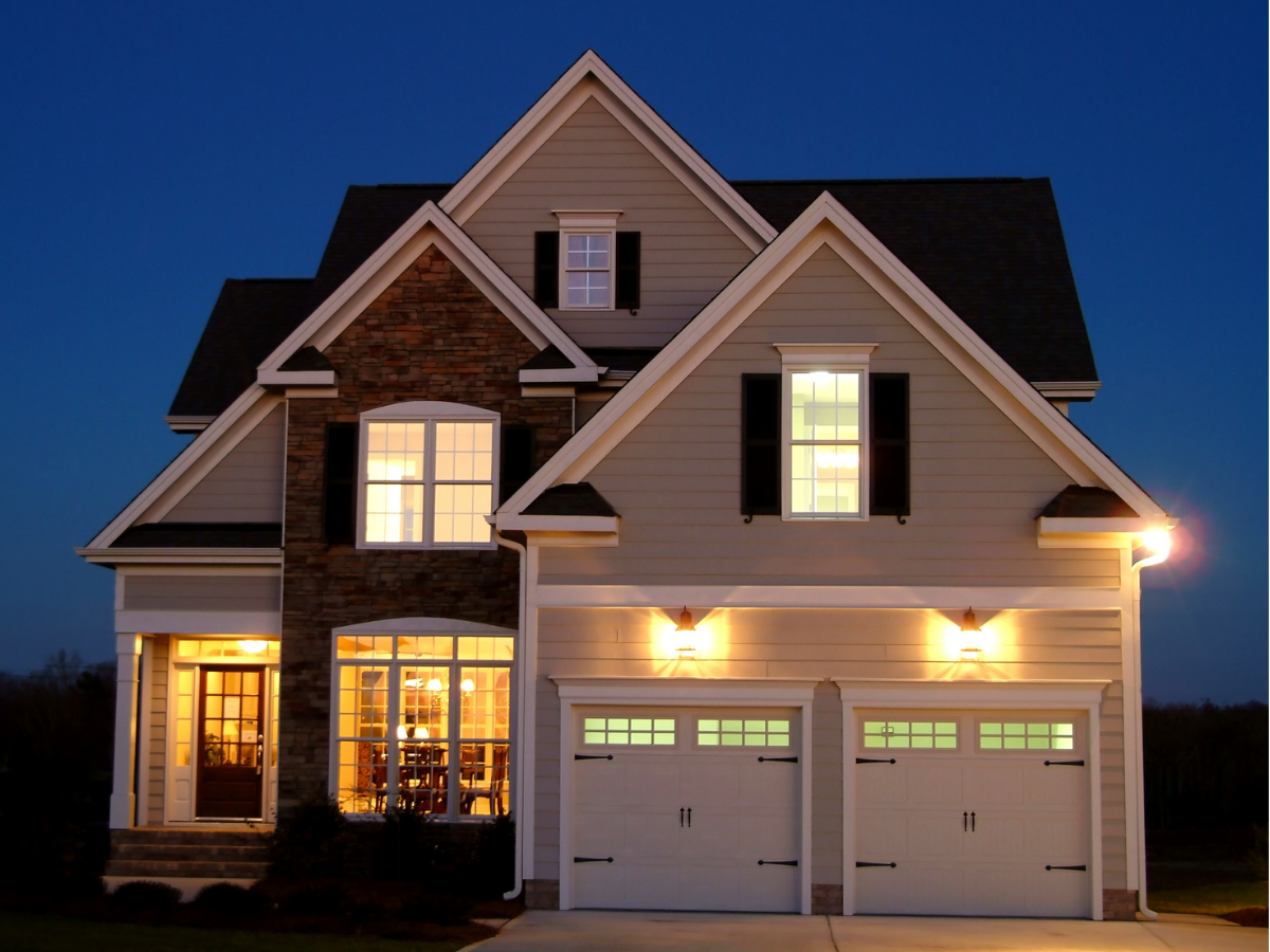 A two-story home at night with lights on in the interior and exterior of the home. 