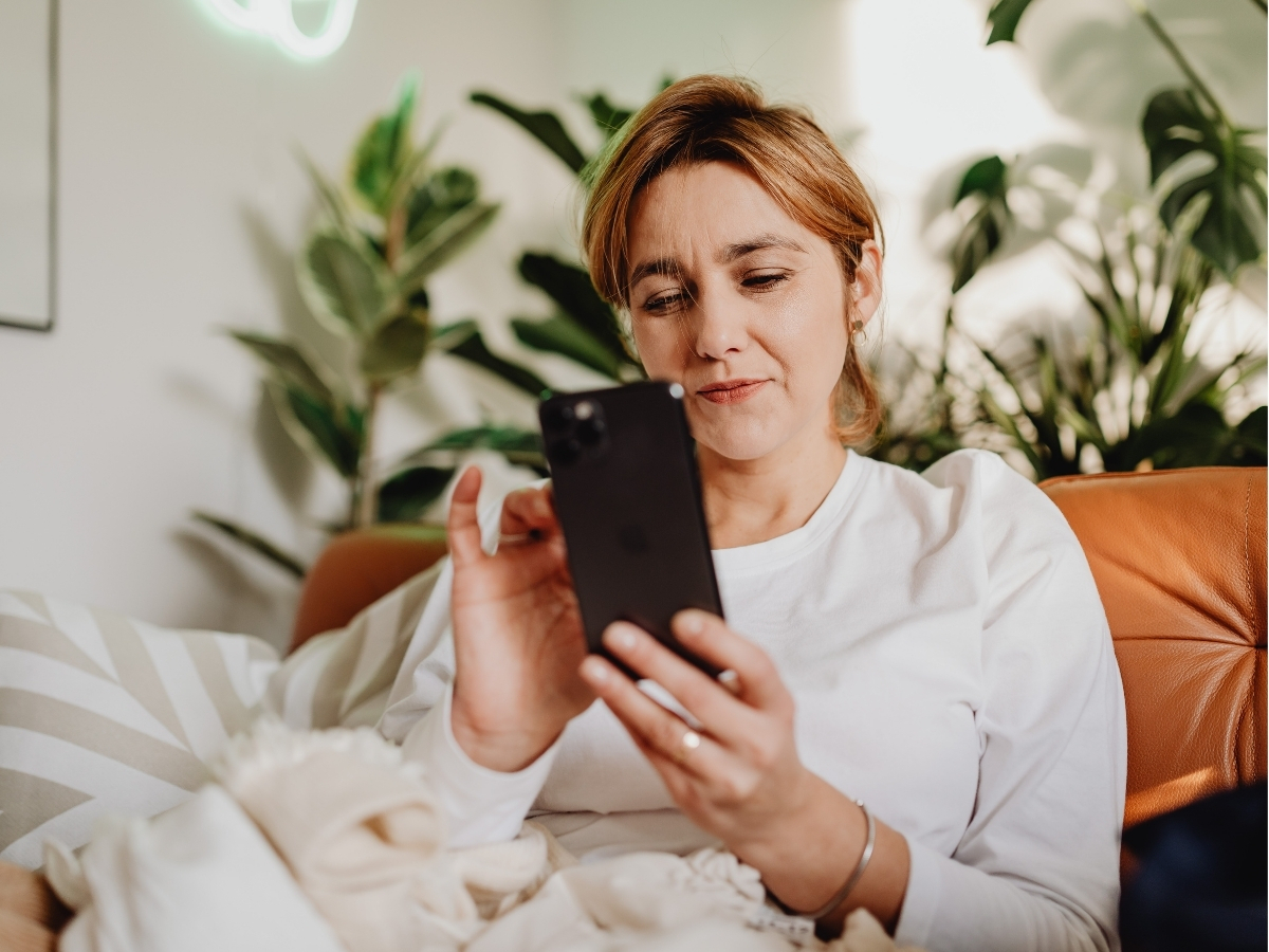 Woman adjusting thermostat on smartphone.