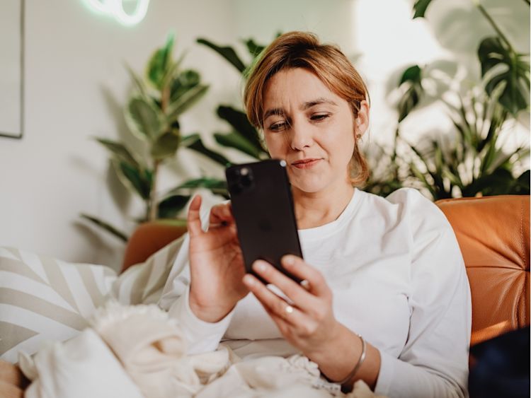 Woman adjusting thermostat on smartphone.
