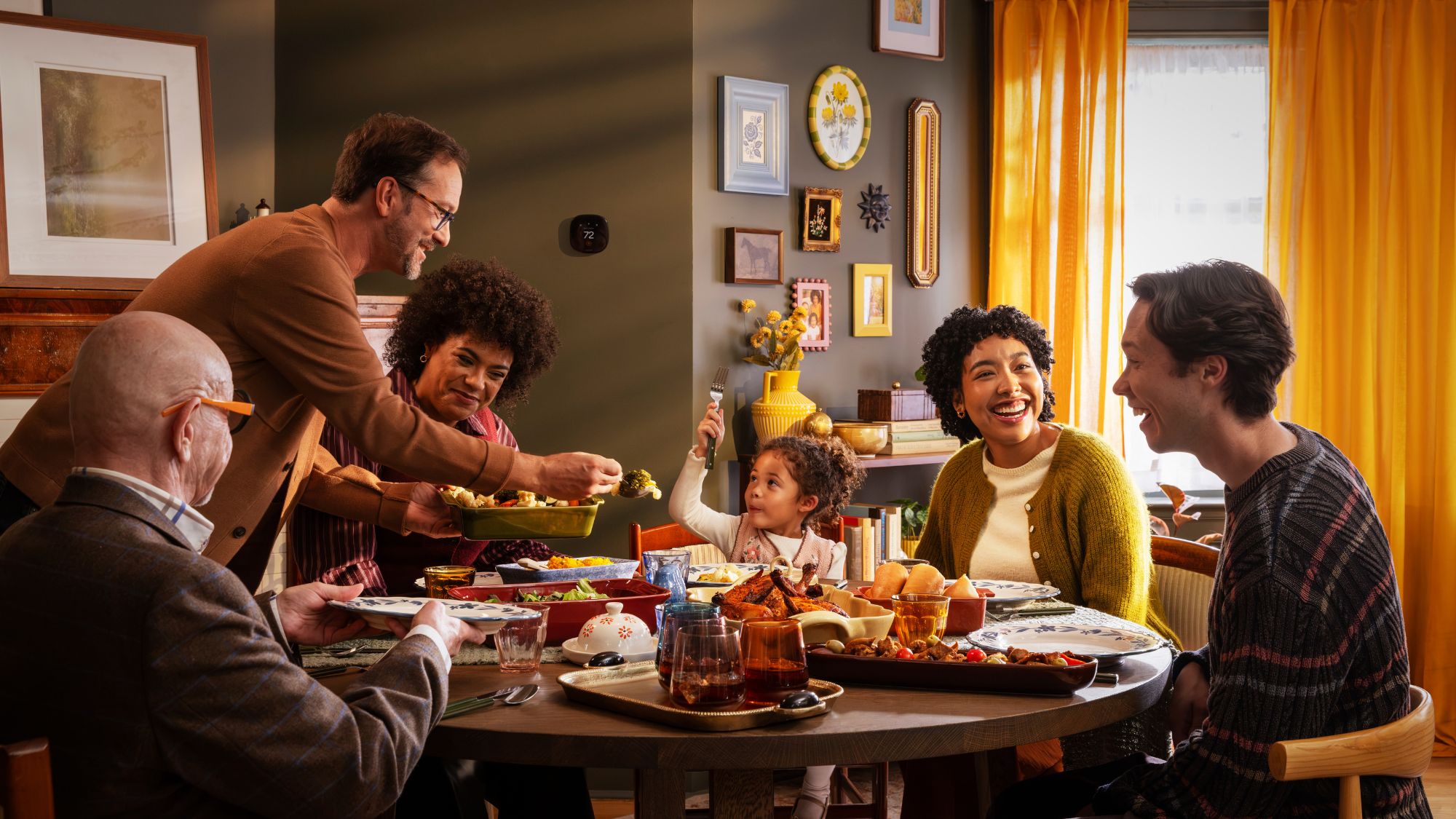 A family gathers around the dinner table to share a meal in a warm, inviting home, with an ecobee smart thermostat visible on the wall.